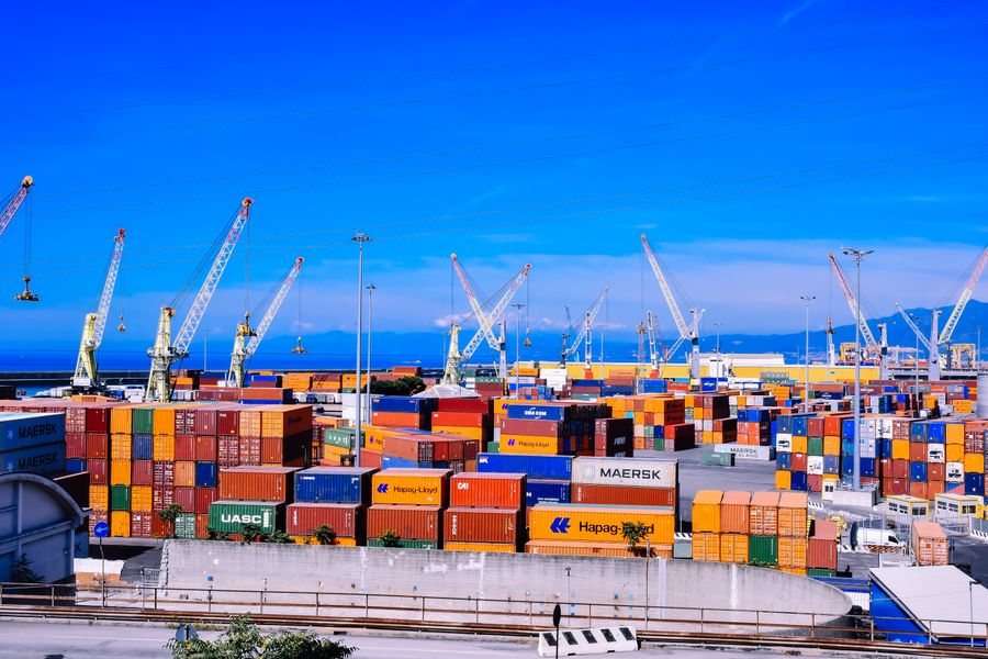 Illustrative image of international trade: shipping containers and cranes at a port.